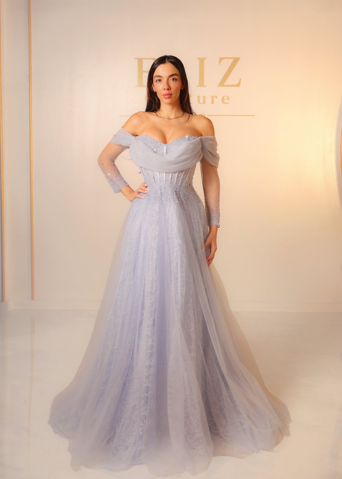 A woman modeling an off-the-shoulder light lavender tulle formal gown with a fitted bodice and full skirt, FAIZ COUTURE