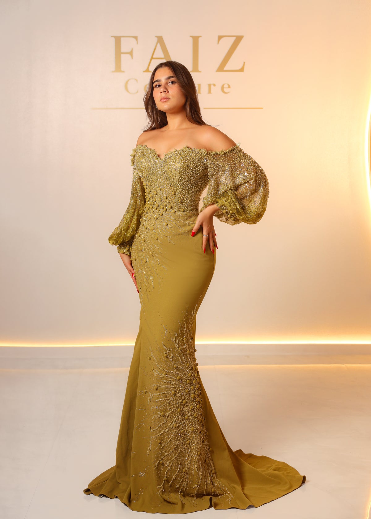 A woman models an off-the-shoulder olive green evening gown with intricate beadwork and embroidery, FAIZ COUTURE